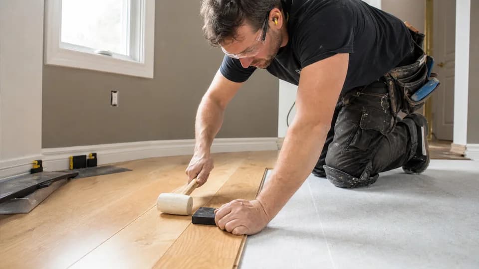 Flooring installer fitting a wood plank